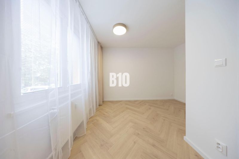 NOVO ZREKONŠTRUOVANÝ 4-IZBOVÝ BYT V TICHOM PROSTREDÍ - 78 m² - NOVÉ ME - Izba v 4-izbovom byte s bielymi stenami a podlahou s dreveným dekorom.