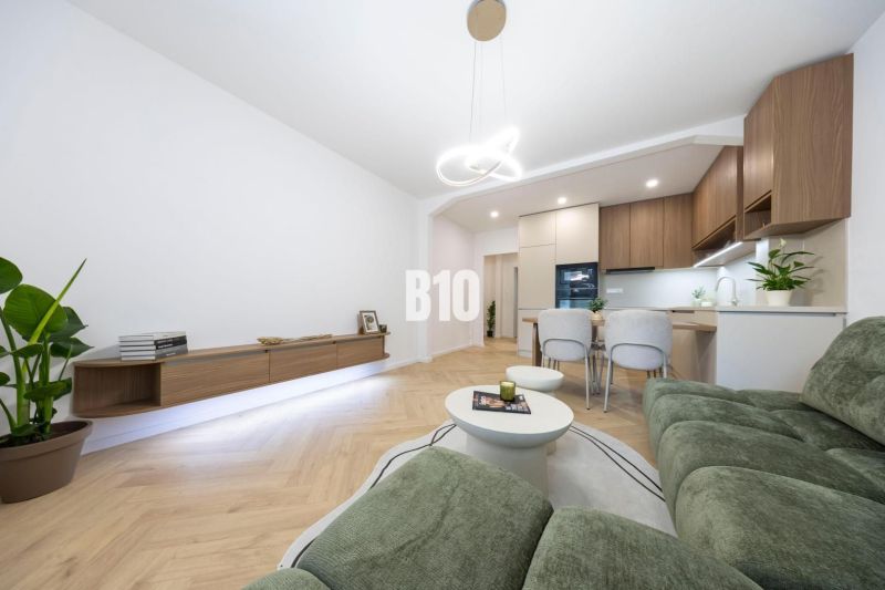 NOVO ZREKONŠTRUOVANÝ 4-IZBOVÝ BYT V TICHOM PROSTREDÍ - 78 m² - NOVÉ ME - Obývacia izba v 4-izbovom byte s pohovkou a podlahou s dreveným dekorom.