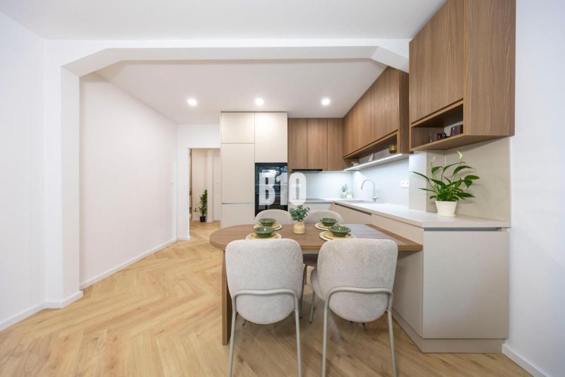NOVO ZREKONŠTRUOVANÝ 4-IZBOVÝ BYT V TICHOM PROSTREDÍ - 78 m² - NOVÉ ME - Kuchyňa v 4-izbovom byte s podlahou s dreveným dekorom a moderným nábytkom.