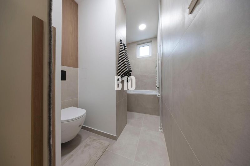 NOVO ZREKONŠTRUOVANÝ 4-IZBOVÝ BYT V TICHOM PROSTREDÍ - 78 m² - NOVÉ ME - Kúpeľňa v 4-izbovom byte s vaňou, toaletou a dlažbou v neutrálnych tónoch.