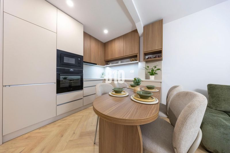 NOVO ZREKONŠTRUOVANÝ 4-IZBOVÝ BYT V TICHOM PROSTREDÍ - 78 m² - NOVÉ ME - Kuchyňa so vstavanými spotrebičmi a jedálenským stolom v 4-izbovom byte, podlaha s dreveným dekorom.