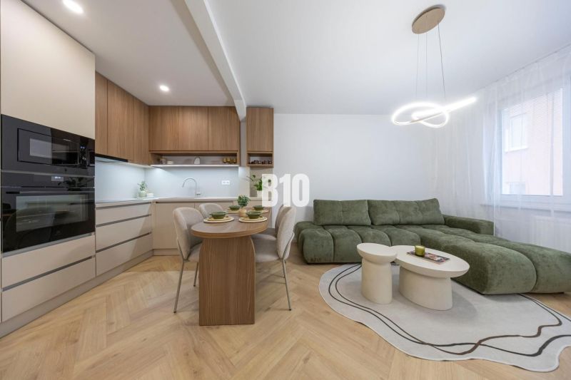 NOVO ZREKONŠTRUOVANÝ 4-IZBOVÝ BYT V TICHOM PROSTREDÍ - 78 m² - NOVÉ ME - Kuchyňa v 4-izbovom byte s podlahou s dreveným dekorom a zelenou sedačkou.