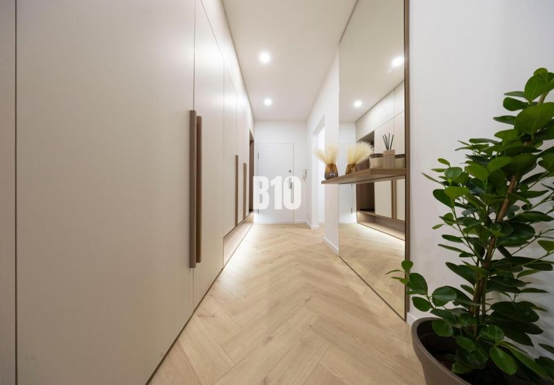 NOVO ZREKONŠTRUOVANÝ 4-IZBOVÝ BYT V TICHOM PROSTREDÍ - 78 m² - NOVÉ ME - Chodba s podlahou s dreveným dekorom, veľkým zrkadlom a vstavanými skriňami v 4-izbovom byte.