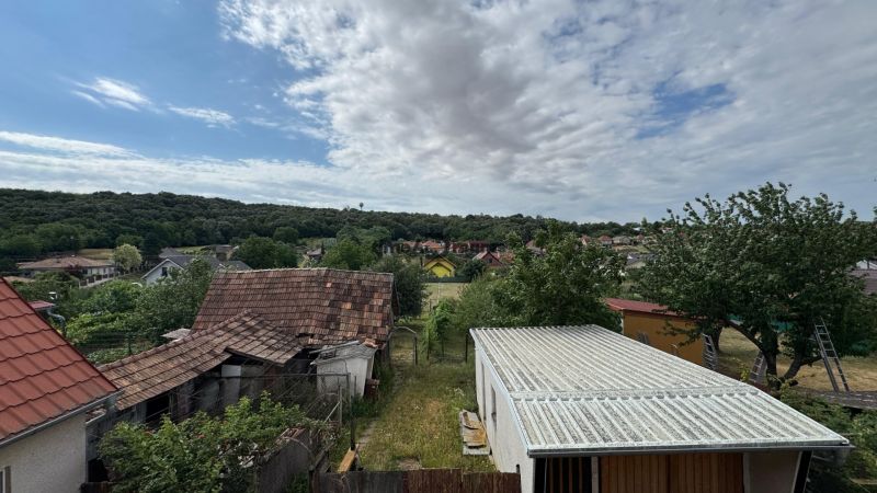 NA PREDAJ poschodový Rodinný dom v Jarku - Pohľad z rodinného domu v Jarku na záhradu, strechy a lesnatú krajinu.