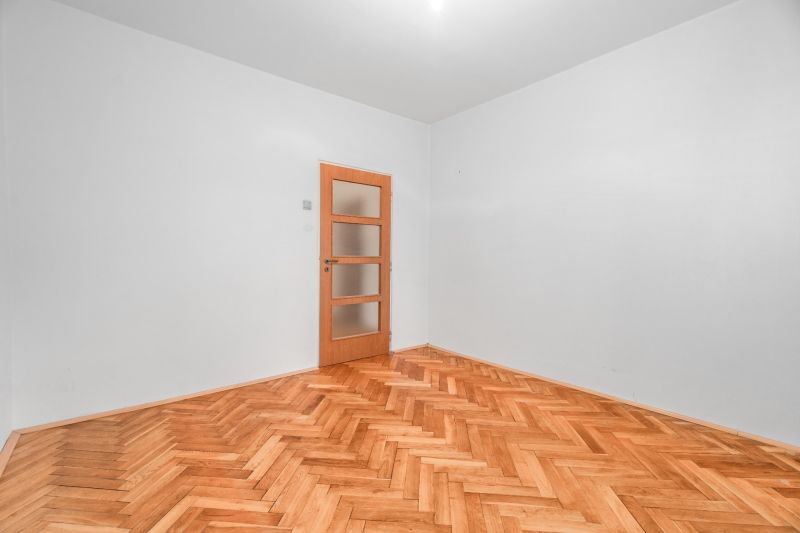  3-izbbyt s veľkou loggiou vo vyhľadávanej lokalite Bratisl - Prázdna miestnosť s drevenou podlahou a dverami v 3-izbovom byte.