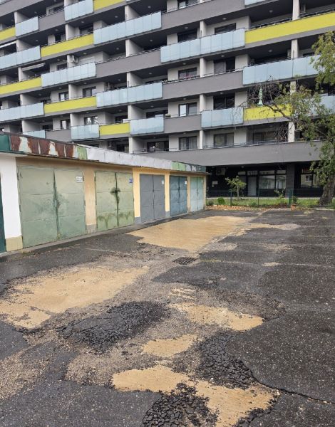 Garáž na Exnárovej ulici  - Garáže na Exnárovej ulici v Bratislave-Ružinove pred bytovým domom s poškodeným asfaltom.