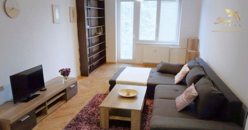 Svetlý, kompletne zariadený 2i byt s balkónom blízko centra Trenčína - Obývačka v 2-izbovom byte s podlahou s dreveným dekorom a pohodlnou pohovkou.