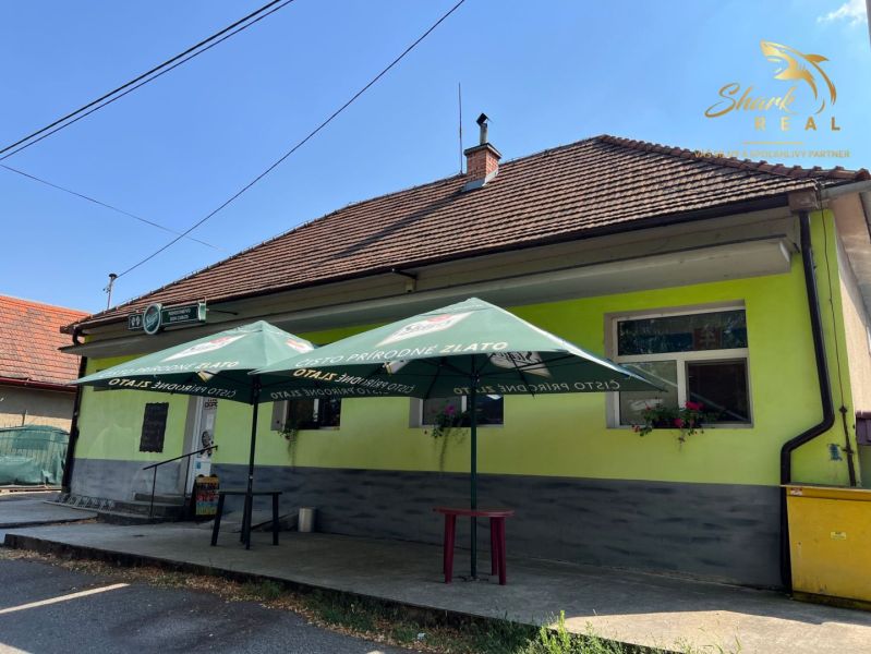 Obchodný priestor s ubytovacím zariadením - Exteriér gastronomických priestorov v Kozárovciach so slnečníkmi nad vchodom.