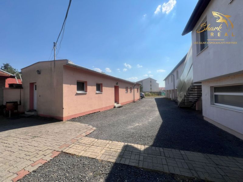 Obchodný priestor s ubytovacím zariadením - Exteriér gastro priestorov v Kozárovciach s dláždeným a štrkovým povrchom.