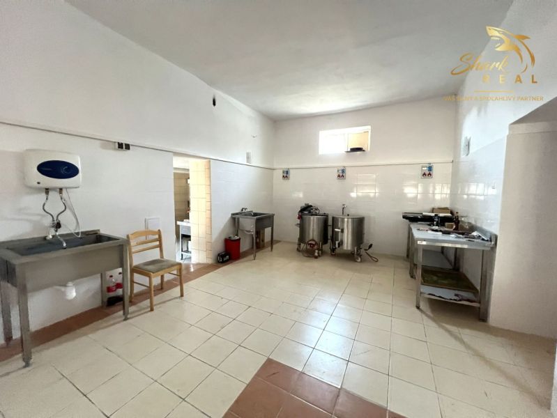 Obchodný priestor s ubytovacím zariadením - Gastro priestory s nerezovými stolmi a umývadlami, podlaha s keramickými dlaždicami.